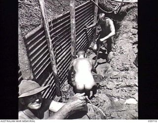 DONADABU, NEW GUINEA. 1943-11-03. SAPPERS OF THE 24TH AUSTRALIAN FIELD COMPANY, ROYAL AUSTRALIAN ENGINEERS DIGGING A TRESTLE FOUNDATION FOR A NEW BRIDGE OVER THE LALOKI RIVER. SHOWN: Q13706 SAPPER ..