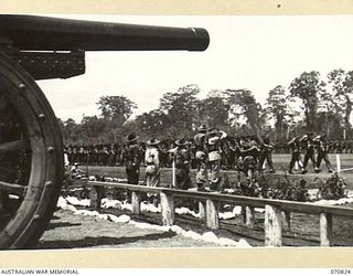 LAE, NEW GUINEA, 1944-03-08. FRAMED BY A CAPTURED JAPANESE FIELD GUN, THE GENERAL OFFICER COMMANDING 2ND AUSTRALIAN CORPS, VX20308 MAJOR-GENERAL F.H. BERRYMAN, CBE, DSO, (1), TAKES THE SALUTE AS ..