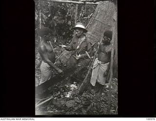 Lae, New Guinea. 1944-07-26. A member of 2/3rd Forestry Company explaining to Australian New Guinea Administraitve Unit (ANGAU) natives the correct method of using a cross cut saw, in the Busu ..