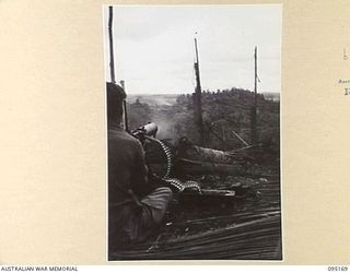 COCONUT KNOLL, KIARIVU, NEW GUINEA, 1945-08-11. A 2/7 INFANTRY BATTALION MEDIUM MACHINE-GUN PUMPING THE SOUTHERN FLANK OF ENEMY-HELD KIARIVU VILLAGE WHICH IS SEEN ON THE HIGHER FEATURE IN THE ..