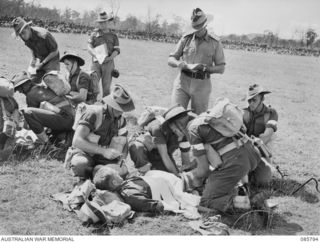 WONDECLA, ATHERTON TABLELAND, QLD. 1945-01-19. PRIVATE F C MILLER, A COY, 2/8 FIELD AMBULANCE, (1), BEING PREPARED FOR THE STRETCHER DURING THE STRETCHER BEARERS' CONTEST WHILE CAPTAIN HOLLYWOOD, ..