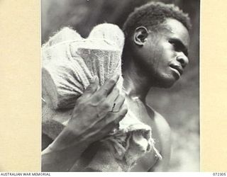 YAULA, NEW GUINEA. 1944-04-11. WANUT, A WAREE BOY, CARRYING SUPPLIES DURING THE ADVANCE OF THE 57/60TH INFANTRY BATTALION TO BOGADJIM