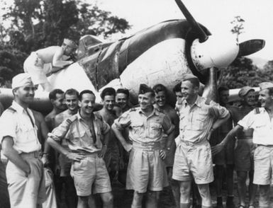 Japanese Zero (Mitsubishi) after landing at Piva Airstrip, Tororina Bougainville Island. After its discovery at the edge of Japanese Kara Airfield in 5th Bougainville by Aust Wirriway Flt. Lt and C Stewart RNZAF photographer, it was tested by NZ ground engineers and flown North by W/CMDR Koeford RNZAF (under propellor). Sqn. Ldr. T Dunn centre, Rmdr RNZAF air and ground crews.