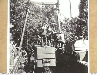 FINSCHHAFEN AREA, NEW GUINEA. 1943-11-04. MEMBERS OF THE 4TH AUSTRALIAN FIELD BAKERY UNLOADING A BAKERS OVEN FROM AN AMPHIBIOUS "DUKW" PREPARATORY TO ESTABLISHING A NEW BAKERY IN THE AREA