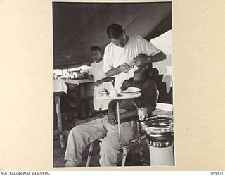 CAPE WOM, WEWAK AREA, NEW GUINEA. 1945-09-01. MAJOR D.R. HEDBERG, COMMANDING OFFICER 2/4 DENTAL UNIT, ATTACHED HEADQUARTERS 6 DIVISION TREATING A PATIENT