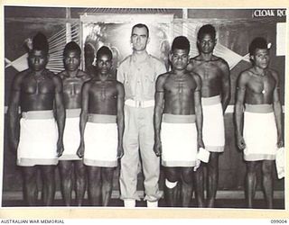 LAE, NEW GUINEA. 1945-11-25. WARRANT OFFICER 2 HIGGINS WITH HIS NATIVE WAITERS AT THE AUSTRALIAN ARMY CANTEENS SERVICE OFFICERS' CLUB. THE CLUB IS SITUATED ON THE BANKS OF THE BUSU RIVER