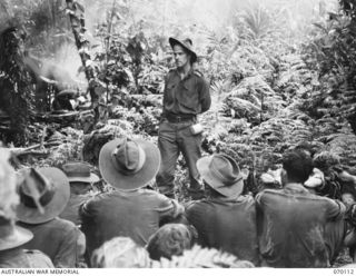 KETOBA, NEW GUINEA. 1944-01-29. VX104114 CHAPLAIN G.T. SAMBELL (CHURCH OF ENGLAND) (1); UNIT PADRE OF THE 57/60TH INFANTRY BATTALION CONDUCTING AN IMPROMPTU PRAYER MEETING ON THE TRAIL NEAR BOKU ..