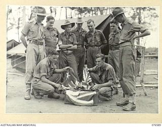 HOSKINS, NEW BRITAIN. 1944-10-10. PERSONNEL OF THE 36TH INFANTRY BATTALION UNPACKING FLAGS PREPARATORY TO HOISTING THE AUSTRALIAN ENSIGN OVER THE NEW UNIT HEADQUARTERS. IDENTIFIED PERSONNEL ARE:- ..