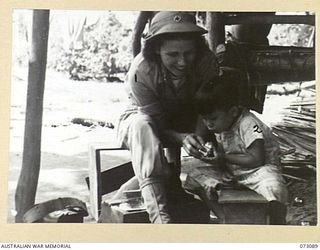 BASU RIVER VALLEY, NEW GUINEA. 1944-05-14. SUSAN TATE, A REPRESENTATIVE OF THE AMERICAN RED CROSS SOCIETY (1), SHOWING A CIGARETTE LIGHTER TO AH TUNG (2), THE SON OF SETO KONG, AT A CHINESE FARMING ..