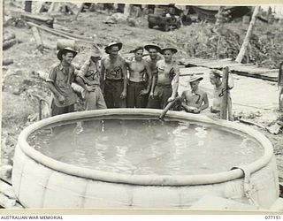 JACQUINOT BAY, NEW BRITAIN. 1944-11-20. PERSONNEL OF THE 9TH FIELD COMPANY ADMIRING A 1200 GALLON WATER TANK WHICH THEY ERECTED IN THE PALMALMAL PLANTATION. IDENTIFIED PERSONNEL ARE:- NX153796 ..