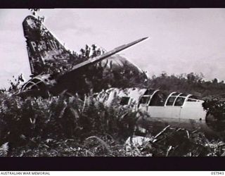 LAE, NEW GUINEA. 1943-10-04. A JAPANESE BOMBER AIRCRAFT TAIL DESTROYED ON THE GROUND AT THE AIRSTRIP IN THE 4TH AUSTRALIAN BASE AREA. THE WRECK OF A ZERO FUSELAGE IS IN THE FOREGROUND ON THE RIGHT