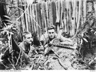 1943-08-11. NEW GUINEA. MOUNT TAMBU FIGHTING. 1ST. CLASS PTE. ARNOLD DRAKE, OF SUMMERVILLE, NEW JERSEY, AND PTE. ERIC HOROBIN, OF COLEDALE, N.S.W., FIRING AN AMERICAN HEAVY MACHINE GUN AT JAPANESE ..