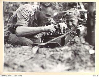 WEWAK AREA, NEW GUINEA. 1945-06-27. LIEUTENANT F.G. CHAPPE, SIGNAL OFFICER (1) AND SIGNALMAN J.J. GRIFFITHS (2), MEMBERS OF 2/8 INFANTRY BATTALION, OPERATING A PHONE DURING THE ATTACK AGAINST THE ..