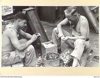 AT SEA. 1944-10-27. DRIVER J.C. POCOCK (1), AND DVR J.W. STRANGE, MILITARY HISTORY SECTION (2), PEEL POTATOES ABOARD THE LIBERTY SHIP SS JAMES OLIVER DURING MOVEMENT TO NEW GUINEA