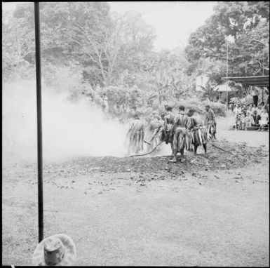 Fijian men, dressed in traditional costumes, burning bundles of leaves on the fire, Fiji, 1966 / Michael Terry