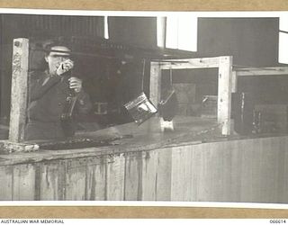 VF515370 PRIVATE J. KINDER, AUSTRALIAN WOMEN'S ARMY SERVICE OF THE TROPIC PROOFING SECTION, 1ST BASE ORDNANCE DEPOT GIVING PARCELS DESTINED FOR NEW GUINEA A FINAL HOT WAX DIP