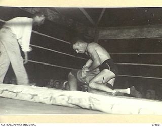 LAE, NEW GUINEA. 1944-07-22. SERGEANT TOD HARDWICKE, AUSTRALIAN MILITARY FORCES (1) AND A FORMER AUSTRALIAN EMPIRE GAMES REPRESENTATIVE, GETS HIS OPPONENT DOWN DURING AN EXHIBITION WRESTLING MATCH ..