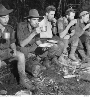 1942-11-23. NEW GUINEA. OIVI. WALKING WOUNDED STOP FOR MEAL ON THEIR WAY BACK TO DRESSING STATION AFTER FIGHTING AT OIVI. (NEGATIVE BY G. SILK)