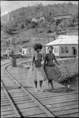 Two women walking on a jetty beside rail lines, Papua, ca. 1923 / Sarah Chinnery