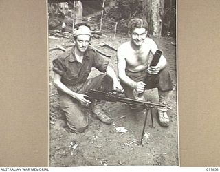 1943-09-14. NEW GUINEA. KOMIATUM RIDGE. CPL. STAN HUSTON, OF BLACKBURN, VIC., WITH A JAPANESE LIGHT MACHINE GUN AND PTE. STAN TAYLOR, OF MELBOURNE, WITH A JAPANESE KNEE MORTAR CAPTURED ON KOMIATUM ..