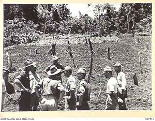 MUSCHU ISLAND, NEW GUINEA. 1945-10-10. MAJOR E.S. OWENS, ASSISTANT ADJUTANT AND QUARTERMASTER GENERAL, HEADQUARTERS 6 DIVISION, AND PARTY, WITH JAPANESE OFFICERS, INSPECTING THE NEWLY TILLED ..