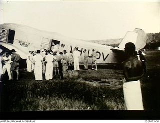 Salamaua, New Guinea. 1941-12. A crowd stands on the airfield watching women and children board the tri-motor Junkers 31 aircraft VH-UOV owned by Bulol Gold Dredging Ltd. Painted on the fuselage ..