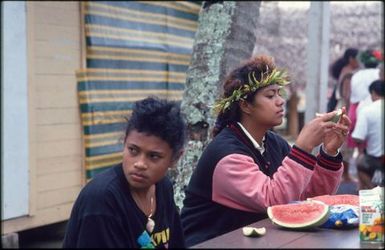 Two young girls eating watermelon