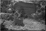 Man and boy sit by a low wall built of coral, eating