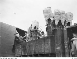 TOROKINA, BOUGAINVILLE, SOLOMON ISLANDS. 1945-03-12. UNIDENTIFIED MEMBERS OF THE 121ST SUPPLY DEPOT PLATOON, AUSTRALIAN ARMY SERVICE CORPS LOAD PETROL SUPPLIES FROM A 3 TON VEHICLE TO A DOUGLAS C47 ..