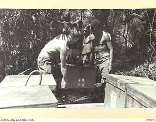 GOALING RIVER AREA, WEST NEW GUINEA. 1944-01-25. AUSTRALIAN NEW GUINEA ADMINISTRATIVE UNIT NATIVES AND MEMBERS OF THE 9TH DIVISION SALVAGE UNIT LOADING ABANDONED JAPANESE MEDICAL EQUIPMENT INTO A ..