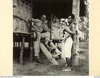 WAMBIT, NEW GUINEA, 1944-03-01. NGX 305 WARRANT OFFICER 1, P.M. SWANSON, DEPUTY ASSISTANT DIRECTOR NATIVE LABOUR AT WAMPIT, HEADQUARTERS, COMMANDER ROYAL ENGINEERS (A.I.F.), (1), PICTURED WITH A ..