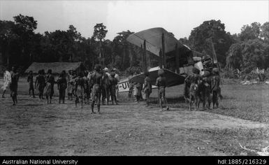 Group of people surrounding aeroplane (DH61) near Atemble Mission