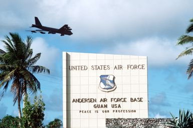 A view of the sign at the main entrance to the base. In the background, a B-52 Stratofortress aircraft comes in to land