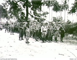 THE SOLOMON ISLANDS, 1945-09. A WORKING PARTY OF JAPANESE SOLDIERS FROM NAURU ISLAND, ARMED WITH LONG HANDLED SHOVELS, ABOUT TO SET OFF ON BOUGAINVILLE ISLAND UNDER THE WATCHFUL EYES OF AUSTRALIAN ..