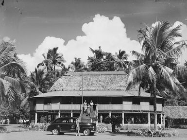 [View of a two story fale and an automobile]