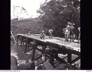 DONADABU, NEW GUINEA. 1943-11-03. SAPPERS OF THE 24TH AUSTRALIAN FIELD PARK COMPANY, ROYAL AUSTRALIAN ENGINEERS "LEVELLING OFF" THE PLANKS OF THE NEW BRIDGE OVER THE LALOKI RIVER. SHOWN: QX50209 ..