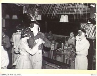 LAE AREA, NEW GUINEA, 1945-08-22. DANCERS AND THE BAND AT THE MASKED MYSTERY BALL HELD AT NO. 3 SERGEANTS' MESS, HEADQUARTERS FIRST ARMY; APPROXIMATELY 60 AUSTRALIAN WOMEN'S ARMY SERVICE SERGEANTS ..