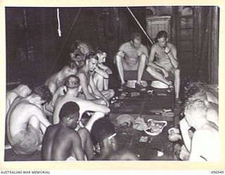 BOUGAINVILLE, 1945-09-17. OFFICERS AND MEN ABOARD THE DEBORAH PASS THE TIME WITH A GAME OF "HOUSIE-HOUSIE". THE VESSEL, IN NUMA NUMA HARBOUR, HAS BROUGHT THE SURRENDER COMMISSIONER AND PARTY FROM ..