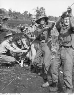 AITAPE, NORTH EAST NEW GUINEA. 1944-04-24. RAAF OFFICERS, GROUP CAPTAIN (GP CAPT) D. CANDY, GP CAPT WIGGINS, AND SQUADRON LEADER IVOR MCIVON PULL ON A ROPE TO HELP RAAF ENGINEERS TO HAUL THE FRAME ..