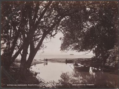 Four people on the shore watching a boat at the Maravari River entrance, Vella Lavella, Solomon Islands, 1906 / J.W. Beattie