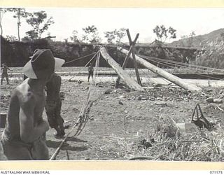 EVAPIA RIVER, NEW GUINEA, 1944-03-15. TROOPS FROM THE 2/4TH FIELD COMPANY, ROYAL AUSTRALIAN ENGINEERS RIG GEAR AND TACKLE TO ERECT THE LARGE MAIN SUPPORT FOR THE SUSPENSION BRIDGE ACROSS THE EVAPIA ..