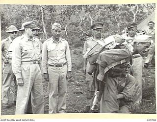 1943-09-15. ALLIED PARATROOPS INVADE THE MARKHAM VALLEY. GENERAL MACARTHUR WATCHES AN AMERICAN PARATROOPER HAVE HIS EQUIPMENT ADJUSTED BEFORE JOINING ONE OF THE GIANT TRANSPORT PLANES WHICH TOOK ..