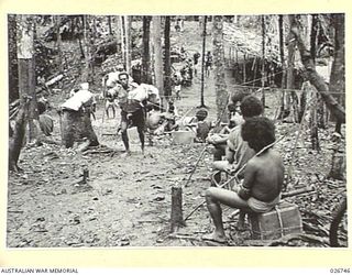PAPUA. 1942-09. NATIVE CARRIERS MOVING ALONG THE TRACK THROUGH THE THICK JUNGLE IN THE UBERI VALLEY WITH SUPPLIES FOR AUSTRALIAN TROOPS IN THE FORWARD POSITIONS. SOME ARE RESTING ON THEIR LOADS IN ..