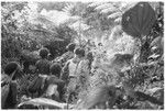 People walking through bush entering hamlet with presentations