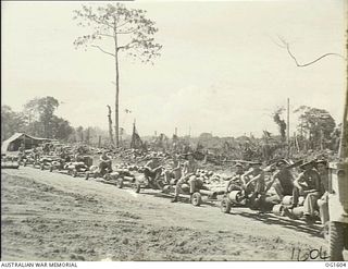 TADJI NEAR AITAPE, NORTH EAST NEW GUINEA. C. 1944-10. A LINE OF BOMBS ON LOW TRAILERS BEING HAULED BEHIND A TRUCK FOR LOADING ONTO BEAUFORT BOMBER AIRCRAFT OF NO. 8 SQUADRON RAAF. MEMBERS OF THE ..