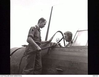 FINSCHHAFEN, NEW GUINEA. 1943-10-30. NX51115 CAPTAIN R. GARNSEY, G111 AIR, 9TH AUSTRALIAN DIVISION, HANDING JAPANESE SWORDS TO PILOT 400848 FLIGHT LIEUTENANT F. A. WATCHORN, NO. 4 ARMY CO-OPERATION ..