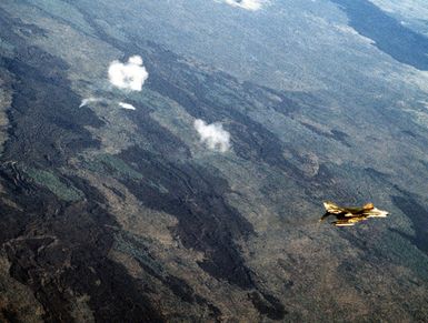 An aerial view of the range as an F-4 Phantom II aircraft flies over a bomb target. The aircraft is assigned to the 3rd Tactical Fighter Wing, involved in Exercise Opportune Journey 4
