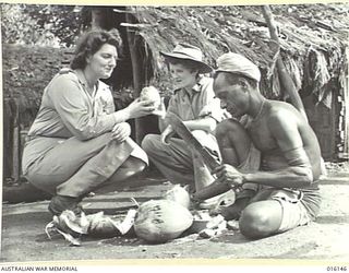 NEW GUINEA. 1943-11-17. MEMBERS OF THE AUSTRALIAN ARMY MEDICAL WOMEN'S SERVICE (AAMWS), NELL BACKHOUSE OF KILLARNEY, QLD AND BETTY GOODWIN OF BELLEVUE HILL, NSW, HAVE A COOLING DRINK OF COCONUT ..