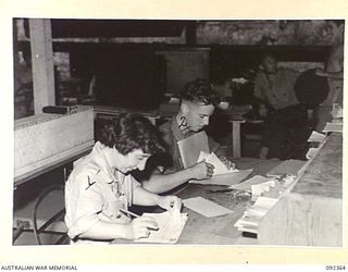 LAE, NEW GUINEA, 1945-05-23. PRIVATE R. MCNEALL, AWAS (1), WITH CORPORAL L. G. WHITEHEAD (2), PROGRESSING ISSUE VOUCHERS AT NO 2 SUB DEPOT, 4 ADVANCED ORDNANCE DEPOT. AWAS PERSONNEL ARE AT LAE TO ..