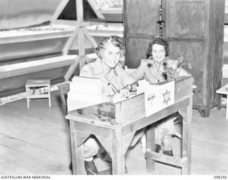 LAE, NEW GUINEA. 1945-10-10. MISS BURCHMORE (1) AND MISS DIAMOND (2), YWCA REPRESENTATIVES, SEATED AT A DECK IN THE YWCA HUT, AUSTRALIAN WOMEN'S ARMY SERVICE BARRACKS